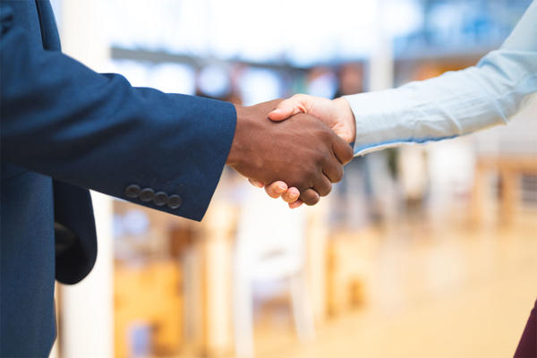 Business people shaking hands with each other in corridor at office