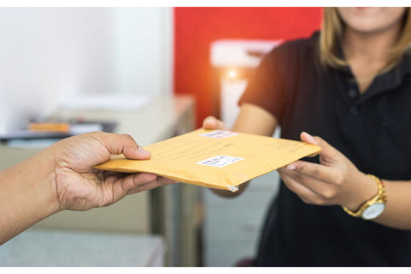 male hand send mail envelope to the female of post office before sending