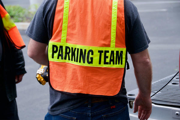 Parking lot attendant wearing bright orange and yellow safety vest