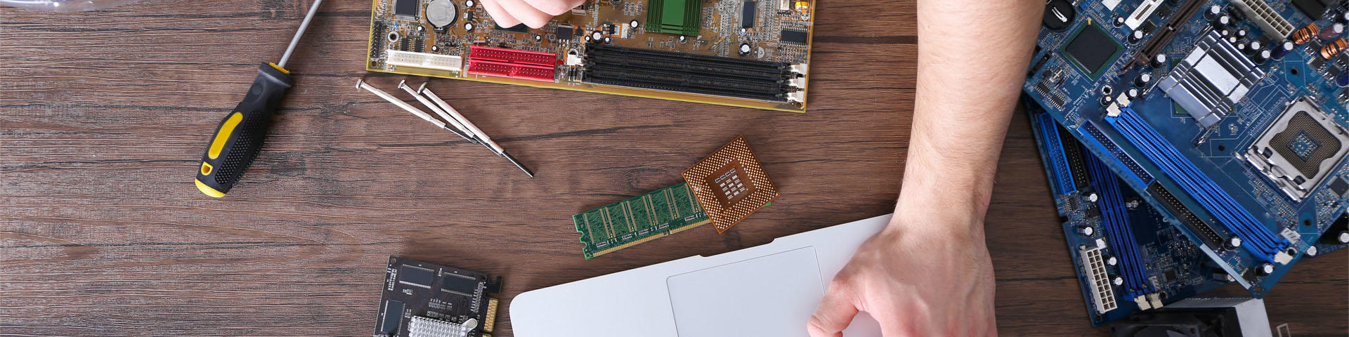 Male hands repairing computer details and using laptop on wooden table, top view