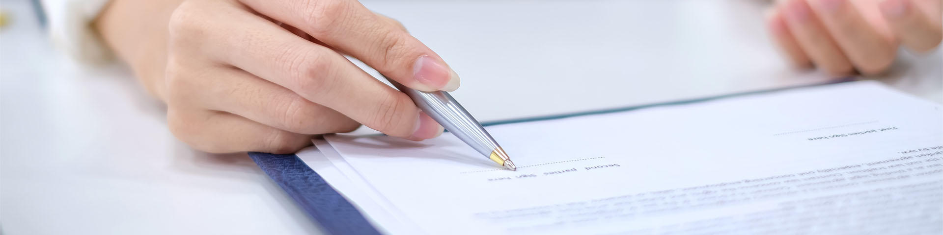 Close-up of a business woman hand pointing signing contract at the office. 